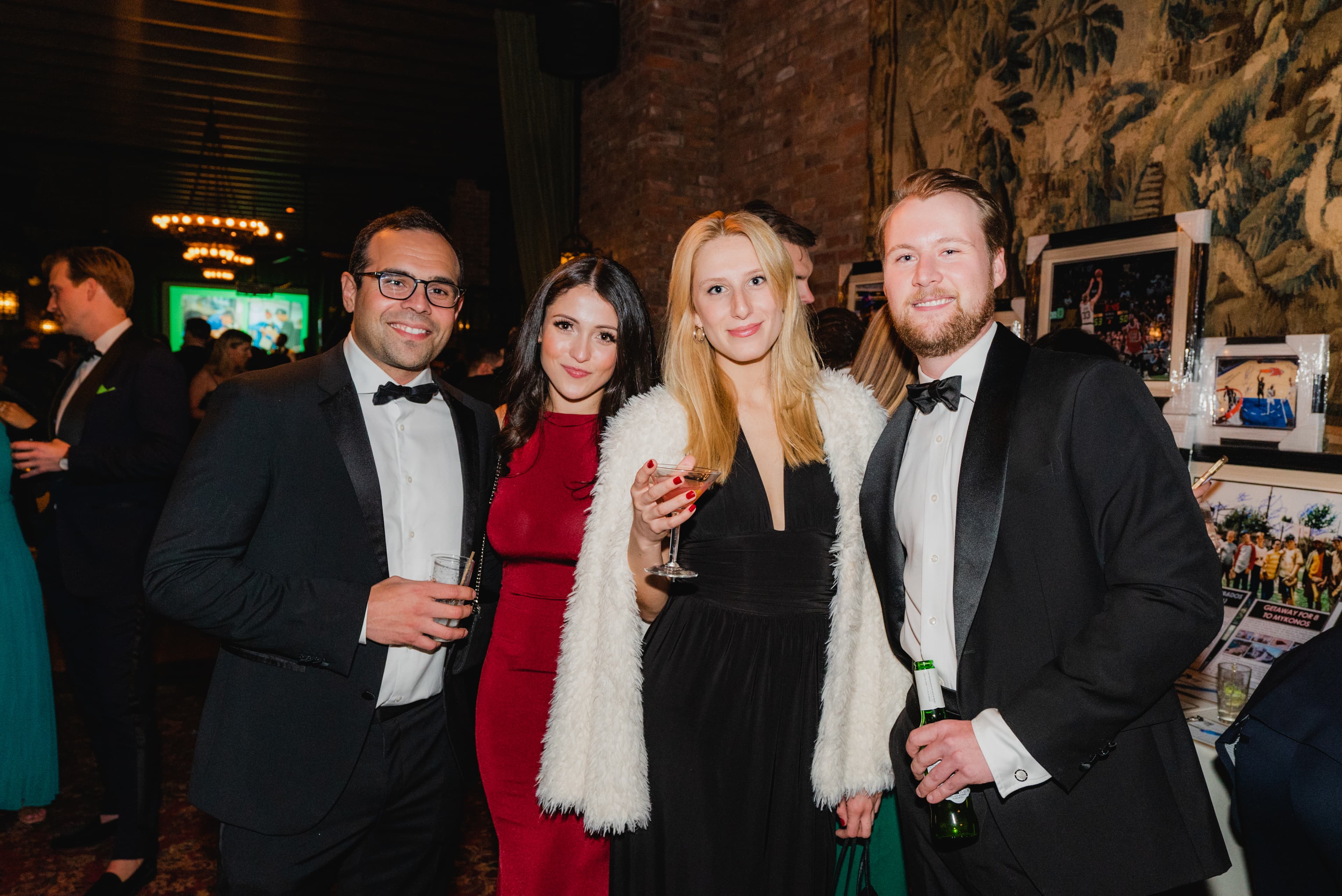 Four guests in formalwear posing together at a black-tie gala